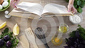 Woman hands holding cooking book table, girl choosing recipe for family dinner