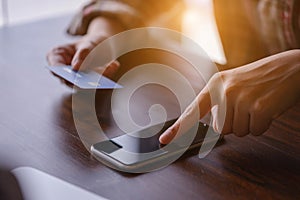 Woman hands holding credit card and using smarth phone.Pays for