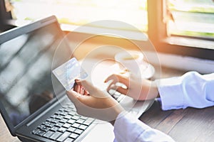 Woman hands holding credit card and using tablet for online shopping in a office table coffee cup background / working people