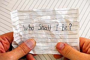 Woman hands holding crumpled lined paper with question Who Shall I Be
