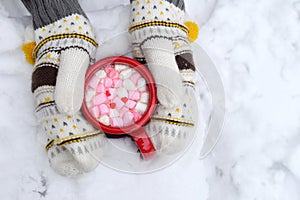 Woman Hands Holding Cup of Hot Chocolate with Marshmallow candies. Knitted mittens and Warm cocoa drink. Hello February or