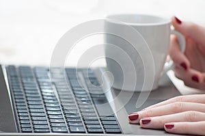 Woman hands holding cup on laptop keyboard