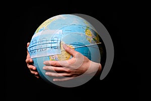 Woman hands holding the Earh globe in the doctor breath medicine mask