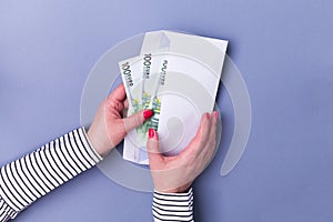 Woman hands holding envelope with cash. Euro banknotes.