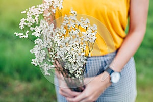 Woman hands holding a flower in green meadow