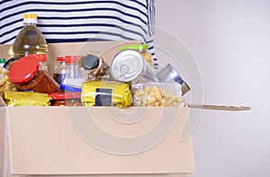 Woman hands holding food donations box with grocery products