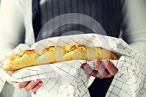 Woman hands holding freshly baked bread. French baguette, bakery concept, homemade food, healthy eating. Copy space