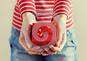 Woman hands holding a gift or present box with bow of red ribbon