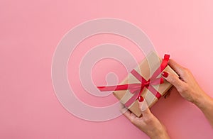 Woman hands holding gift with red ribbon