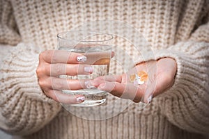 Woman hands holding glass of water and vitamins and medication.B12, D3, selenium