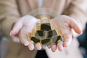 Woman hands holding gold bars stack as secure investment