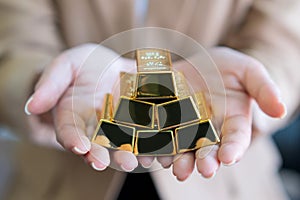 Woman hands holding gold bars stack as secure investment