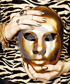 Woman hands holding golden carnival mask, rich luxury manicure and jewelry close up on zebra print