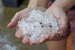 Woman hands holding hail stones in the garden after storm in the summer