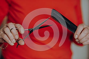 Woman hands holding hair cutting accessories comb and scissors