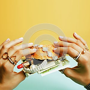 Woman hands holding hamburger with money, jewelry, cosmetic, soc