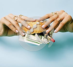 Woman hands holding hamburger with money, jewelry, cosmetic, social issue wealth concept