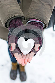 Woman hands holding heart shaped snowball