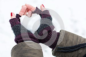 Woman hands holding heart shaped snowball