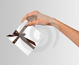 Woman Hands holding Holiday Present White Box with Brown Ribbon on a White Background