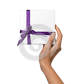 Woman Hands holding Holiday Present White Box with Purple Ribbon on a White Background
