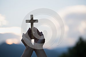 Woman hands holding holy lift of christian cross with light suns