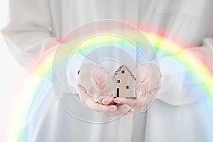 woman hands holding home model with rainbow