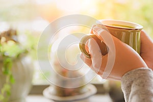 Woman hands holding hot cup of coffee or tea in morning.