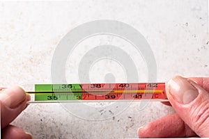 Woman hands holding mercury thermometer on white background. Fever and healthcare concept. Top view