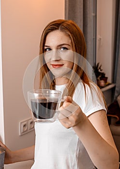 Woman hands holding mug of hot drink. She is smiling and holding a cup of coffee in hand split up in order to inhale the