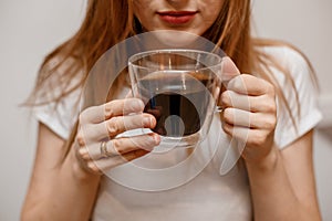 Woman hands holding mug of hot drink. She is smiling and holding a cup of coffee in hand split up in order to inhale the