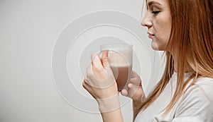 Woman hands holding mug of hot drink. She is smiling and holding a cup of coffee in hand split up in order to inhale the