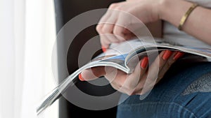 Woman Hands holding open holding magazine. Close up