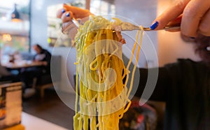 Woman hands holding paglia and fieno spaghetti pasta with two forks ready to serve in a restaurant. photo