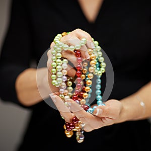 Woman hands holding pearl jewelry, sensual studio shot