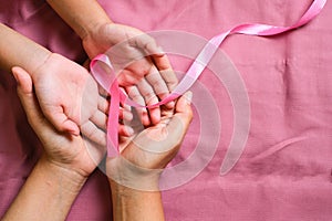 Woman hands holding pink ribbon, breast cancer awareness, October pink concept