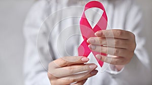 Woman hands holding pink ribbon - breast cancer awareness, October pink concept
