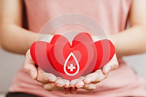 Woman hands holding red heart with blood donor sign. healthcare, medicine and blood donation concept