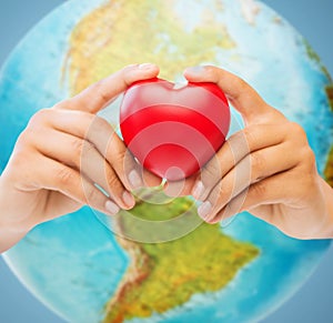 Woman hands holding red heart over earth globe