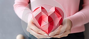 woman hands holding red origami paper heart, concept of express love and St Valentine Day present