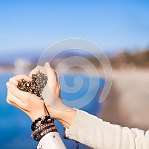 Woman hands holding small stones form heart shape