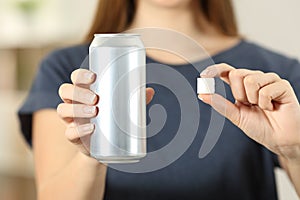Woman hands holding a soda drink can and a sugar cube