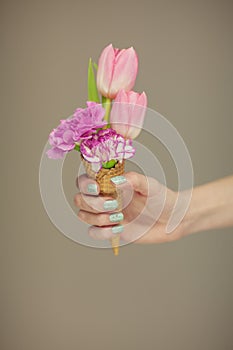 Woman hands holding spring flowers in an ice cream cone, sensual studio shot