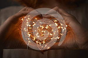 Woman hands holding string of lights in the dark.