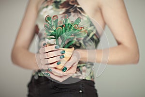 Woman hands holding succulent plant, with perfect green nail polish