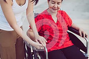 Woman hands holding to asian mature sitting on wheelchair,Take care and suport,Senior insurance concept