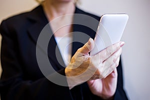 Woman hands holding white mobile phone. Closeup.