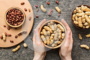 Woman hands holding a wooden bowl with close peanuts. Healthy food and snack. Vegetarian snacks of different nuts