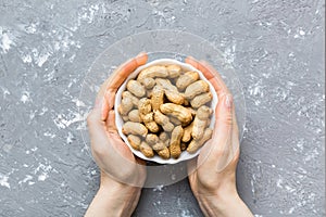 Woman hands holding a wooden bowl with close peanuts. Healthy food and snack. Vegetarian snacks of different nuts