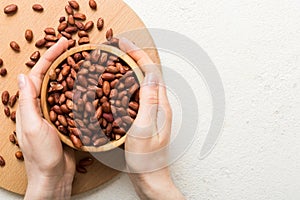 Woman hands holding a wooden bowl with peanuts. Healthy food and snack. Vegetarian snacks of different nuts